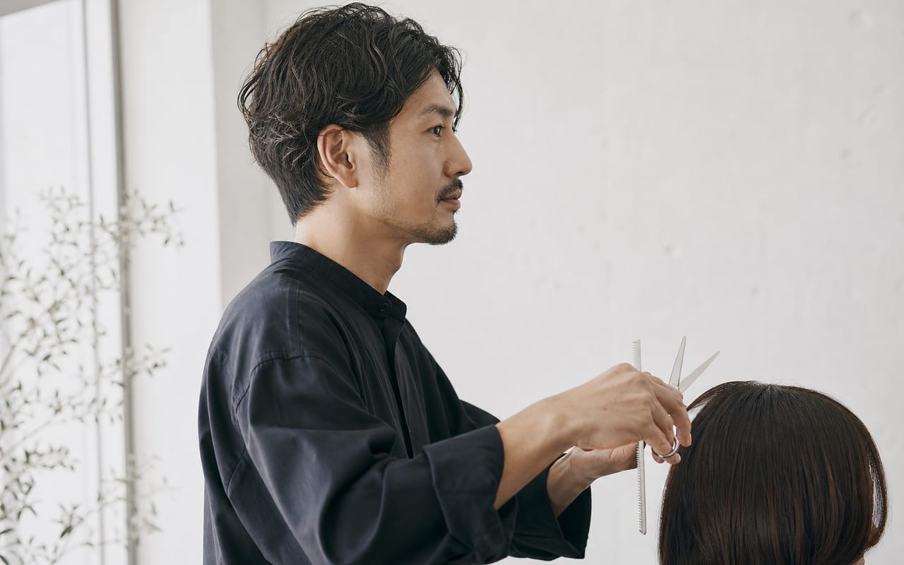 ハサミを手に、光の入るアトリエに立つ早乙女朔の横顔